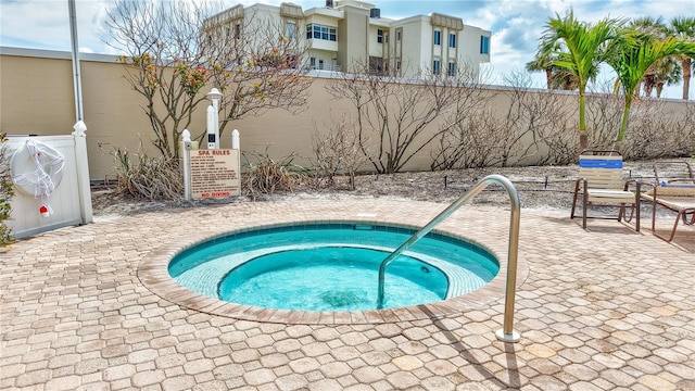 view of swimming pool featuring fence, a community hot tub, and a patio