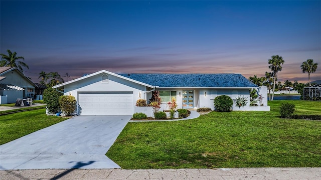 ranch-style home featuring an attached garage, a front lawn, concrete driveway, and stucco siding