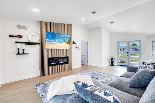 living area featuring visible vents, wood finished floors, french doors, and a glass covered fireplace