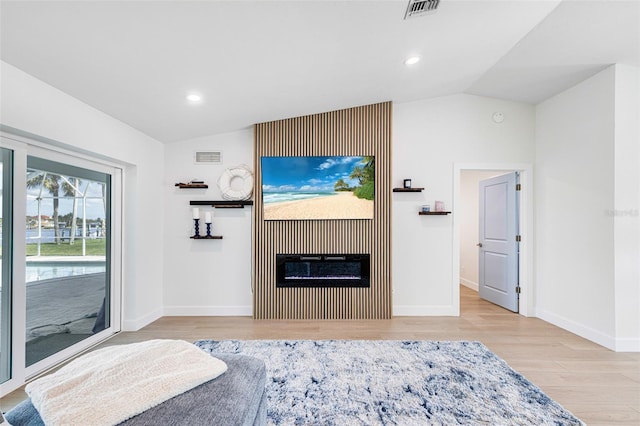 bedroom featuring lofted ceiling, wood finished floors, visible vents, access to outside, and a glass covered fireplace