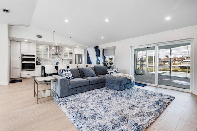 living room with light wood-style floors, recessed lighting, visible vents, and vaulted ceiling