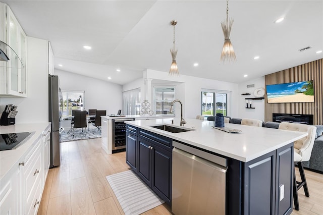 kitchen featuring beverage cooler, an island with sink, appliances with stainless steel finishes, open floor plan, and a sink