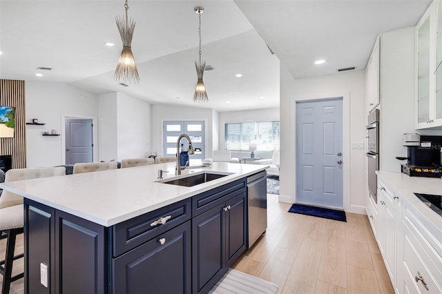 kitchen featuring open floor plan, a sink, dishwasher, and blue cabinets