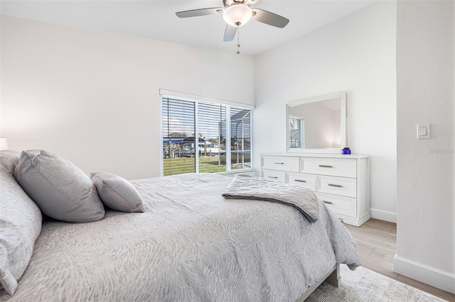 bedroom with light wood-style floors, ceiling fan, and baseboards