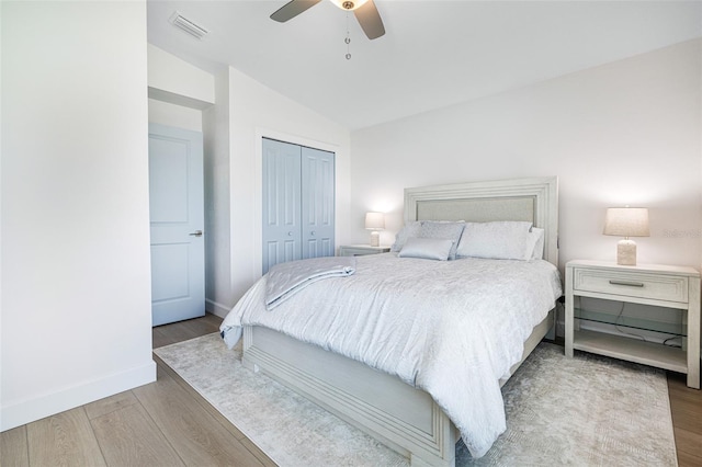 bedroom featuring lofted ceiling, a closet, visible vents, and wood finished floors