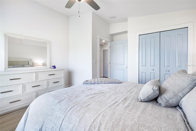 bedroom with ceiling fan, a closet, wood finished floors, and visible vents