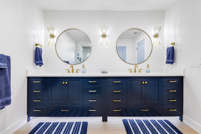 full bath featuring double vanity, baseboards, and a sink