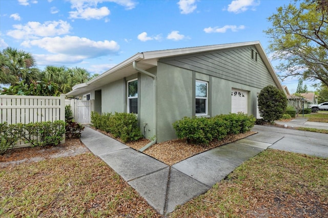 view of property exterior with a garage, fence, and stucco siding