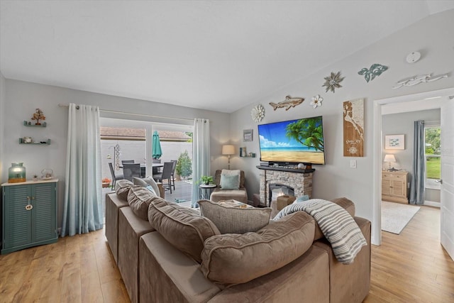 living room featuring lofted ceiling, a fireplace, and light wood-style flooring