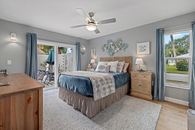 bedroom featuring access to exterior, multiple windows, light wood-style flooring, and baseboards