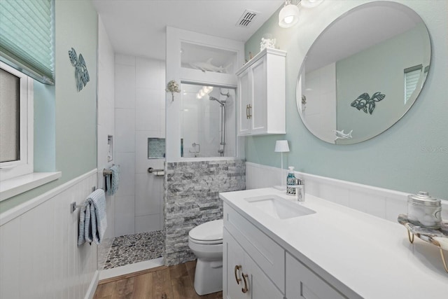 full bath featuring wood finished floors, visible vents, toilet, wainscoting, and a walk in shower