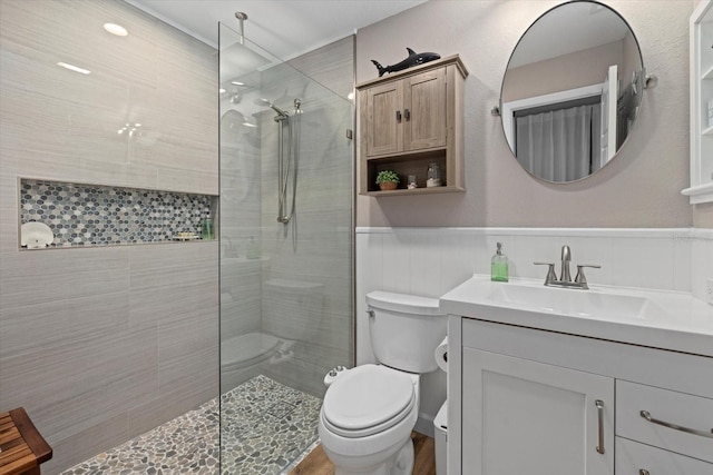 full bathroom with a wainscoted wall, vanity, walk in shower, and toilet