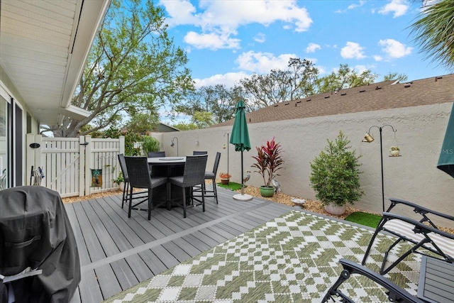 deck with outdoor dining space, a gate, a fenced backyard, and grilling area