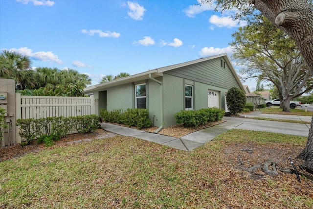 view of property exterior with a garage, fence, driveway, and stucco siding