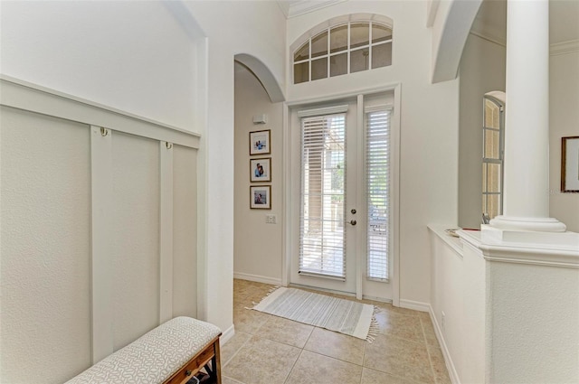 entrance foyer with arched walkways, decorative columns, baseboards, and light tile patterned floors