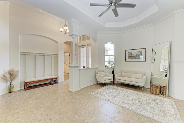 living area with ceiling fan, light tile patterned floors, ornate columns, a raised ceiling, and crown molding