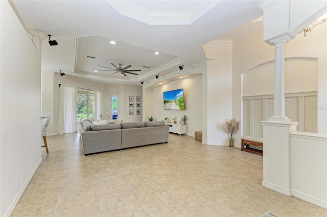 living area with decorative columns, ceiling fan, a tray ceiling, crown molding, and recessed lighting