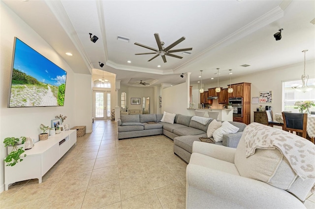 living room featuring ceiling fan with notable chandelier, ornamental molding, light tile patterned floors, and a raised ceiling