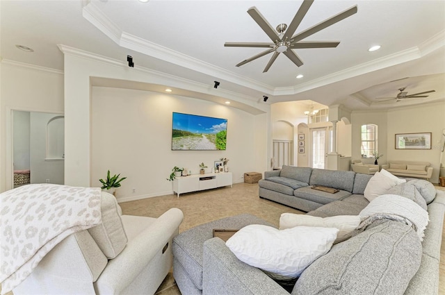 living area with arched walkways, a tray ceiling, recessed lighting, ornamental molding, and ceiling fan