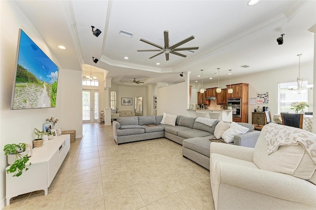 living room featuring ceiling fan with notable chandelier, a tray ceiling, plenty of natural light, and crown molding