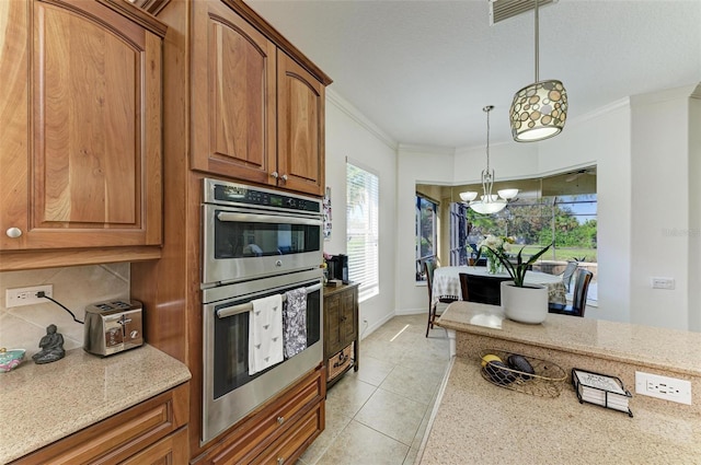 kitchen with double oven, light stone counters, visible vents, ornamental molding, and brown cabinets