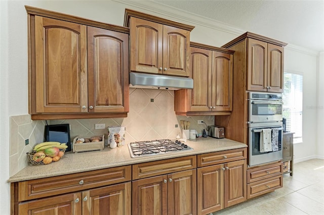 kitchen with under cabinet range hood, tasteful backsplash, ornamental molding, and stainless steel appliances