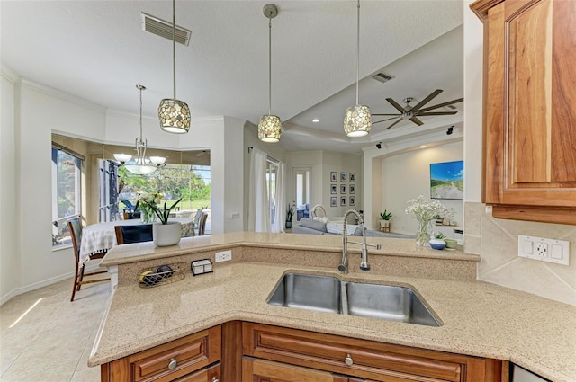 kitchen with light stone counters, a sink, visible vents, and brown cabinets