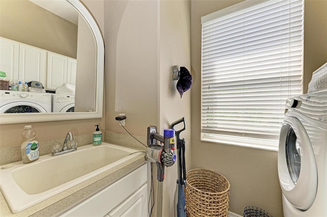 laundry area with washer and clothes dryer, a sink, and cabinet space