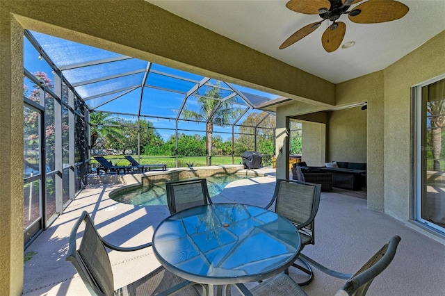 view of patio featuring glass enclosure, outdoor dining space, a ceiling fan, and an outdoor pool