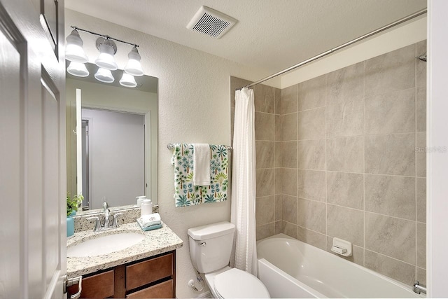 bathroom with vanity, visible vents, shower / tub combo, toilet, and a textured wall