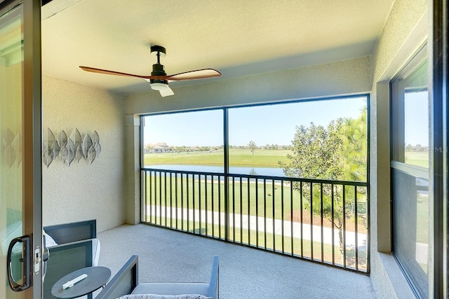 sunroom featuring ceiling fan and a water view