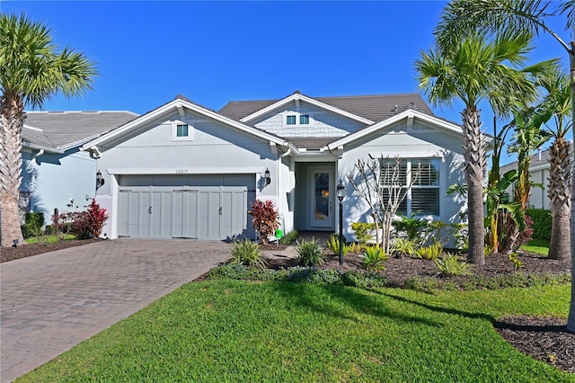 view of front of property with a garage, a front lawn, decorative driveway, and stucco siding