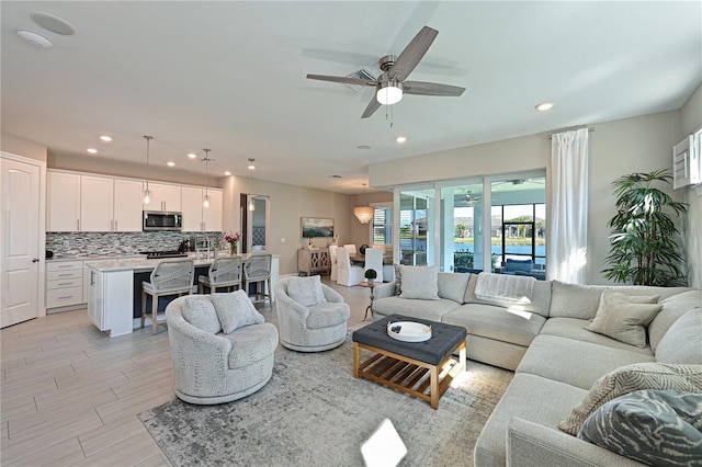 living room with light wood-style flooring, a ceiling fan, and recessed lighting