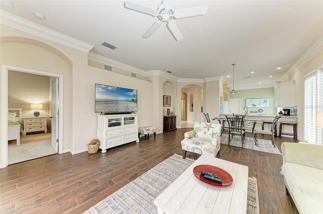 living area featuring arched walkways, ceiling fan, wood finish floors, and visible vents