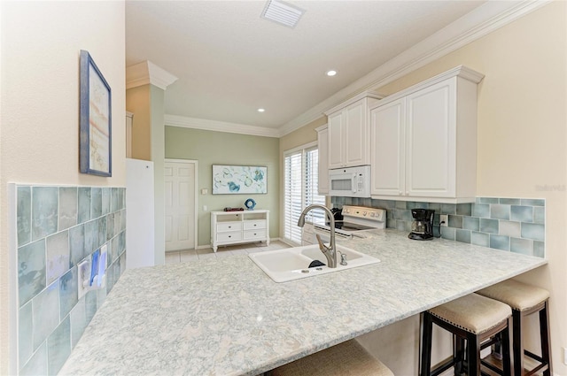 kitchen featuring white appliances, a sink, a kitchen breakfast bar, ornamental molding, and tasteful backsplash