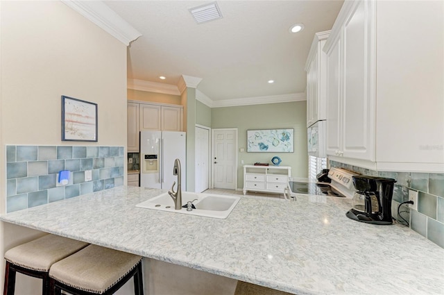 kitchen featuring a peninsula, white appliances, tasteful backsplash, and a sink