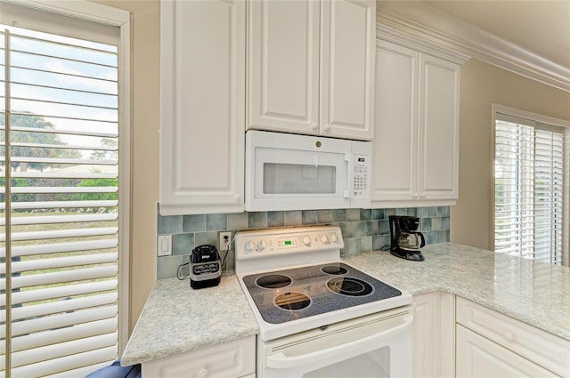 kitchen with white appliances, tasteful backsplash, and white cabinets