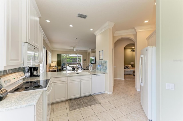 kitchen featuring white appliances, crown molding, arched walkways, and a sink