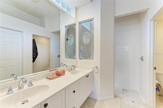 bathroom with double vanity, a sink, toilet, and tile patterned floors