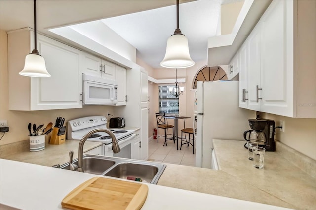 kitchen featuring white appliances, white cabinetry, light countertops, and a sink