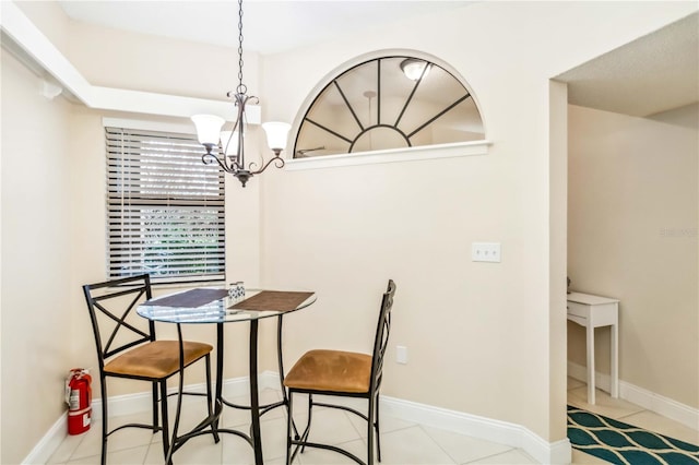 tiled dining space featuring baseboards and an inviting chandelier