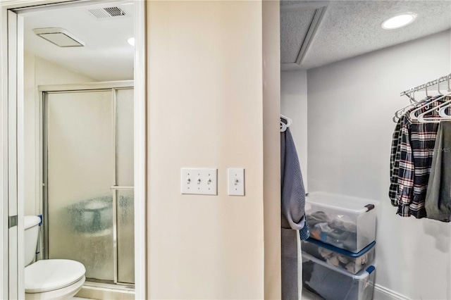 bathroom featuring a textured ceiling, visible vents, a shower stall, and toilet