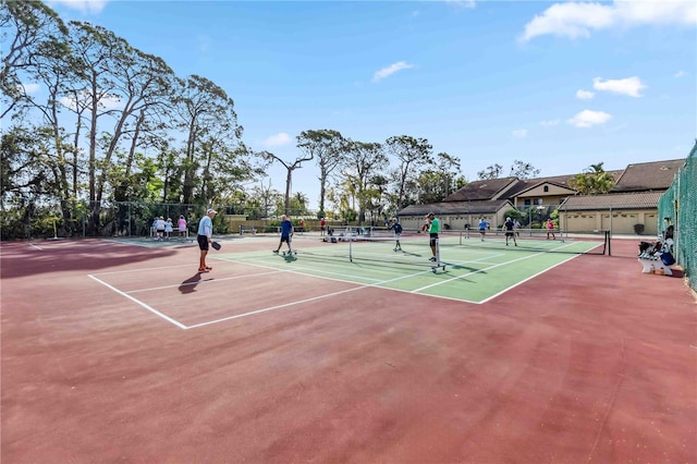 view of tennis court featuring community basketball court and fence