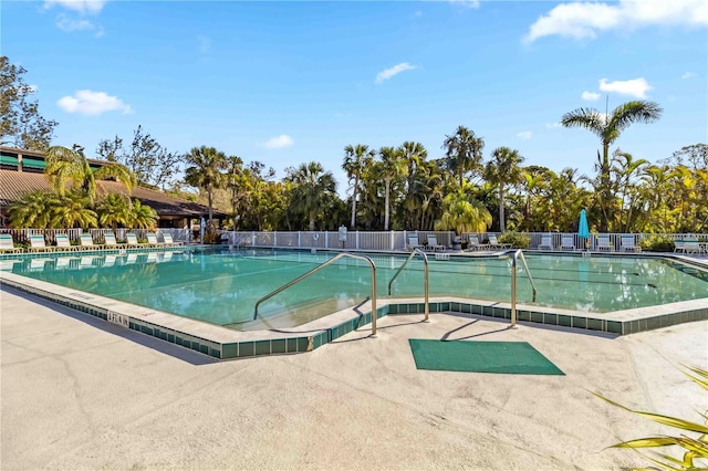 community pool with a patio area and fence