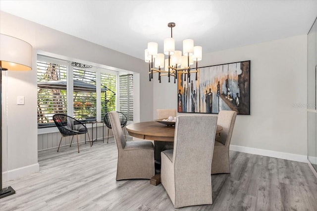 dining room featuring a chandelier, baseboards, and wood finished floors