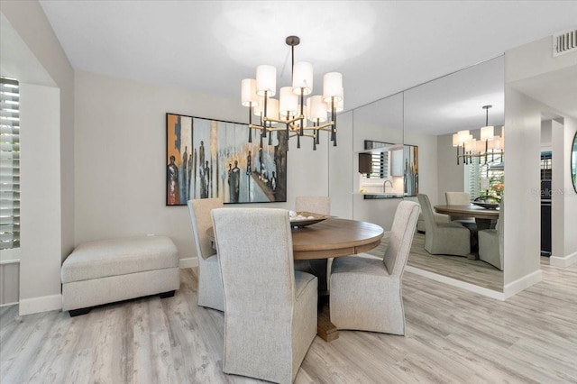 dining room featuring visible vents, a notable chandelier, baseboards, and wood finished floors