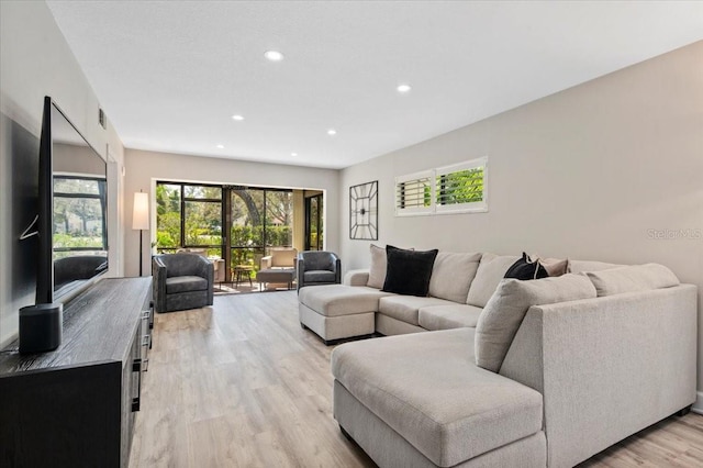 living area with light wood-type flooring, a healthy amount of sunlight, visible vents, and recessed lighting