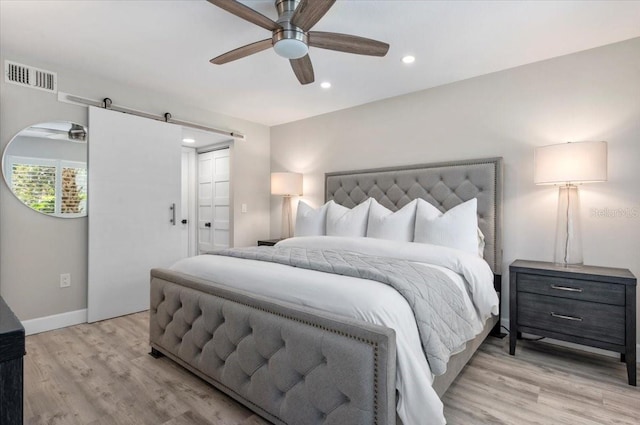 bedroom featuring recessed lighting, visible vents, a barn door, light wood-style floors, and baseboards