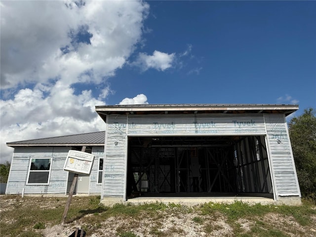 exterior space featuring a garage, metal roof, and an outdoor structure