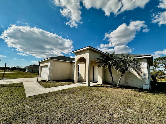 view of front of property featuring driveway, an attached garage, a front lawn, and stucco siding